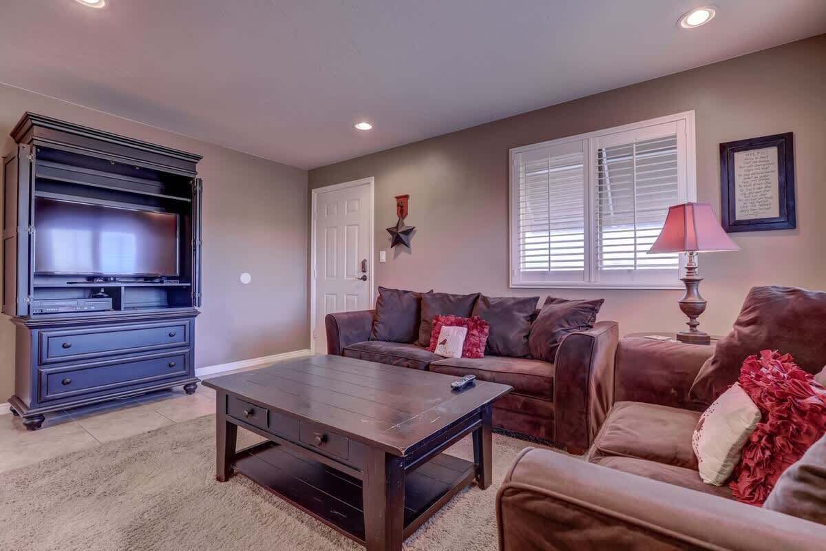 A living room with a dark wooden coffee table, a brown leather sofa, and a dark wooden entertainment center.