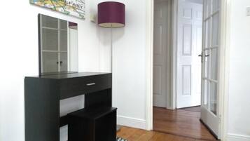 A room with a black vanity, a mirror, a purple floor lamp, and a patterned rug.