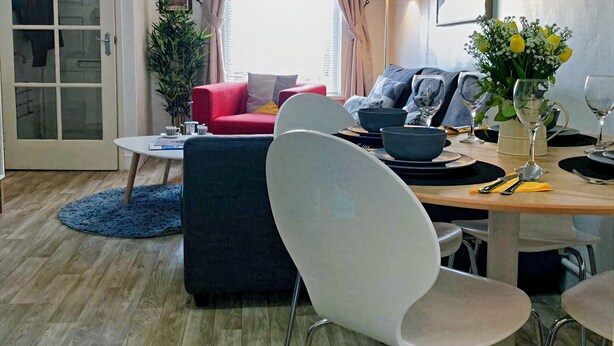 Un salon moderne avec un coin repas, comprenant un canapé, des fauteuils, une table basse et une table à manger pour deux personnes.