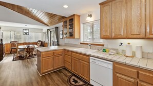 A modern kitchen with wooden cabinets, a dishwasher, and a dining area with a table and chairs.
