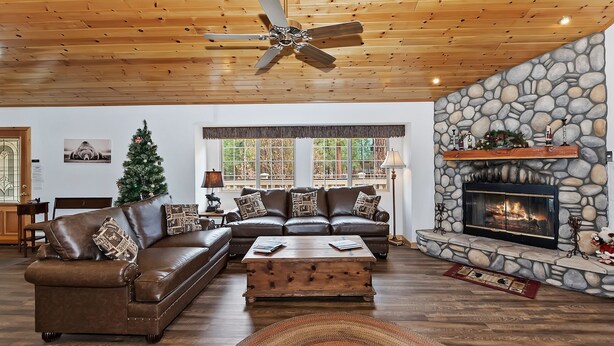 A spacious living room with a leather sectional sofa, a wooden coffee table, and a stone fireplace.