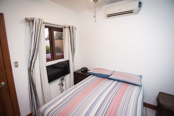 Une chambre à coucher comprenant un lit, une table de chevet, un téléviseur et un appareil de climatisation.