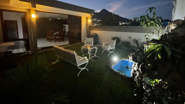 Un patio exterior con piscina, zona de estar y vistas del paisaje circundante.