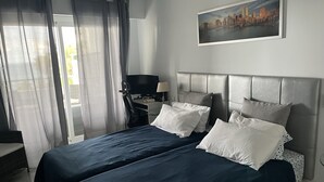 A hotel room with a bed, a desk, a chair, and a painting on the wall. - Holiday Apartment with seaview (Marbella)