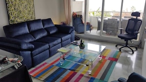 A living room with a blue sofa, a glass coffee table, and a colorful striped rug. - Holiday Apartment with seaview (Marbella)