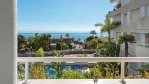 A balcony with a pool, a view of the sea, and a building with balconies and plants. - Holiday Apartment with seaview (Marbella)