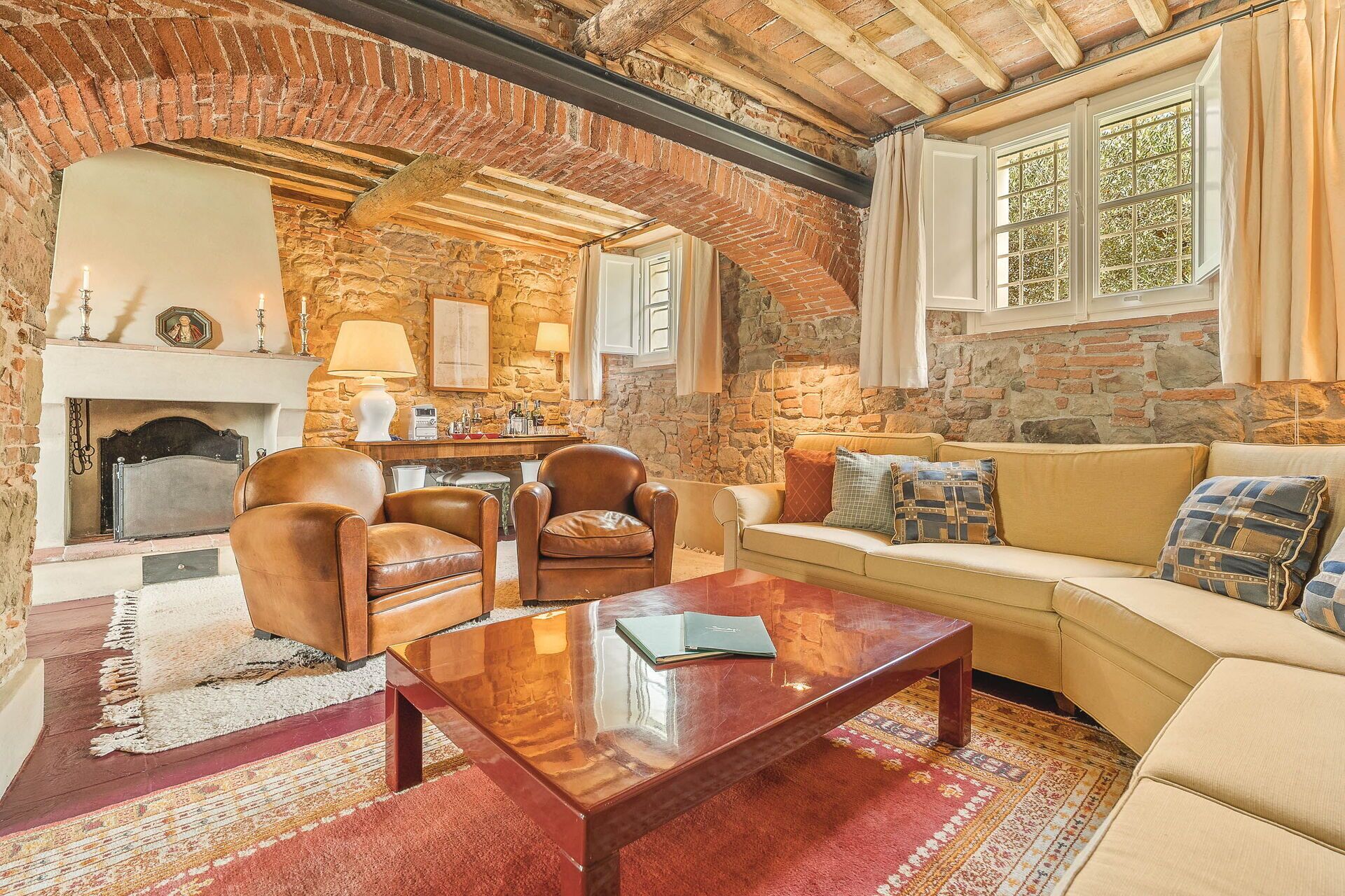 A cozy living room with a stone fireplace, leather armchairs, a sofa, and a coffee table.