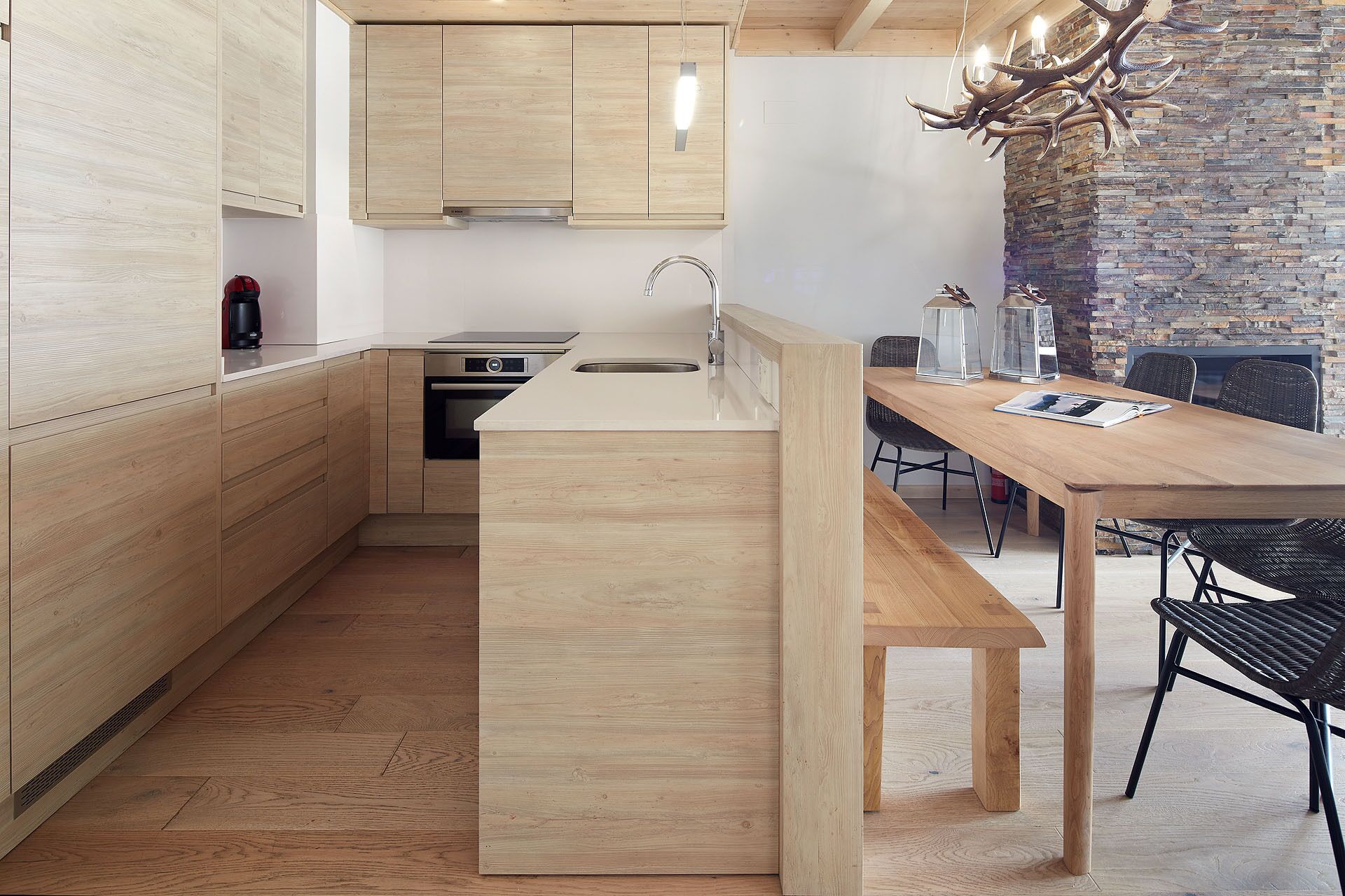 Una cocina moderna con armarios de madera, horno empotrado y una isla grande con pileta.