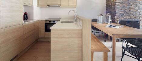 Una cocina moderna con armarios de madera, horno empotrado y una isla grande con pileta.