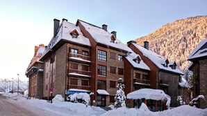 A multi-story hotel with a stone facade, balconies, and snow-covered surroundings.