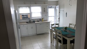 Una cocina con armarios blancos, un lavabo y una zona de comedor con una mesa y sillas.