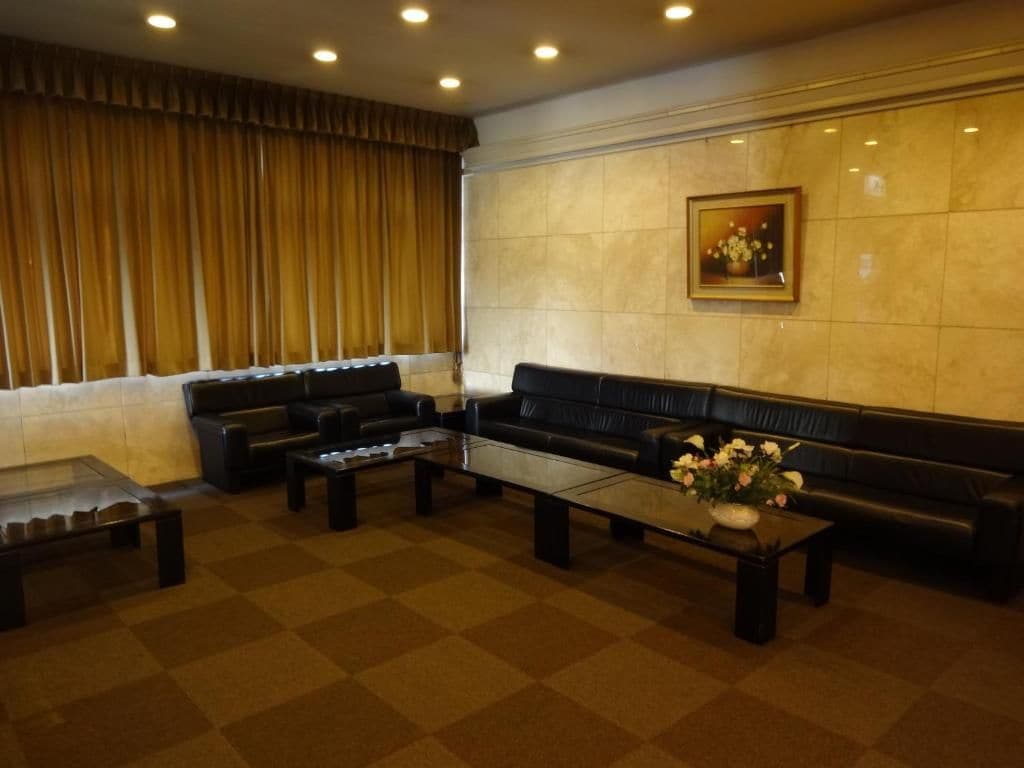 Eine Lobby mit einer Couch, zwei Couchtischen und einer Blumenvase.