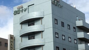 A modern hotel building with multiple balconies and a sign indicating it is the Haneda Inn.