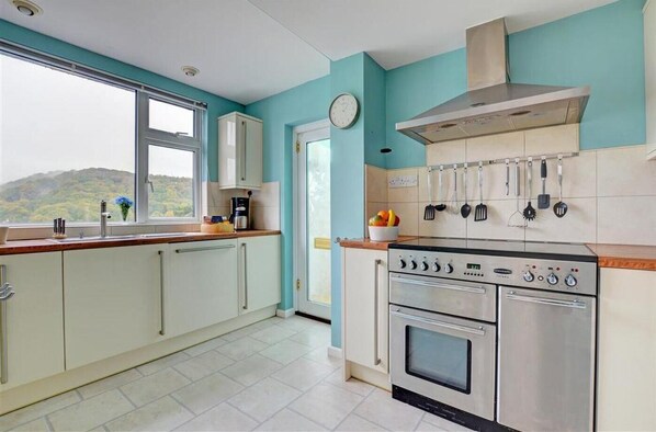 A kitchen with a stove, oven, and hanging utensils.