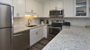 A modern kitchen with white cabinets, stainless steel appliances, and a granite countertop. - Say Aloha to Island Life! Pool View Suite w/Kitchen Ease, WiFi–Kamaole Sands 6308 (KIHEI)