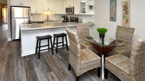 A modern kitchen with white cabinets, stainless steel appliances, and a central island with stools. - Say Aloha to Island Life! Pool View Suite w/Kitchen Ease, WiFi–Kamaole Sands 6308 (KIHEI)