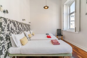 Une chambre d’hôtel avec deux lits, une grande fenêtre et un luminaire suspendu moderne.
