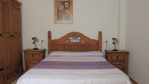 Ein Schlafzimmer mit einem hölzernen Bett, zwei Nachttischen, einem Holzschrank und einem Gemälde an der Wand.