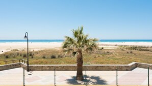 A beach view with a palm tree, a lamp post, and a wooden walkway. - Beachfront apartment in Tarifa with pool (Tarifa)