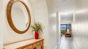 A hallway with a wooden console table, a large mirror, and a potted plant.