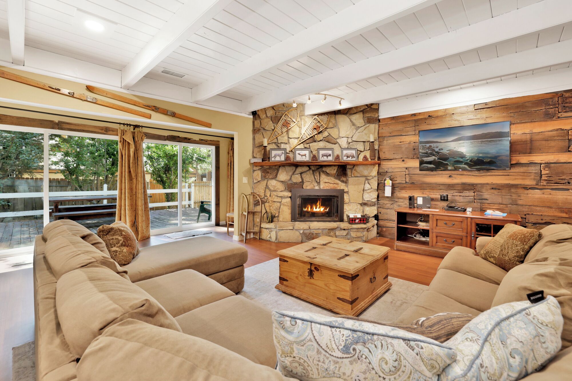 Cozy mountain living room with a stone fireplace, comfy seating, and smart TV—perfect for relaxing evenings, movie nights, and warm cabin vibes after outdoor adventures.