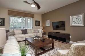 A living room with a sectional sofa, a coffee table, a TV, and a cabinet.