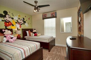 A bedroom with two beds, a ceiling fan, a window with blinds, and a dresser.