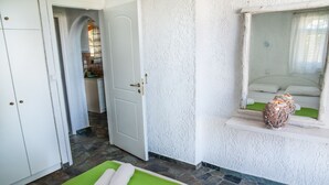 A room with a bed, a green mat, a white door, and a stone floor. - Independent condo, with stunning view just a heartbeat away from the beach (Kokkonion)