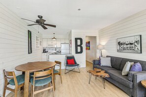 A compact living space with a kitchenette, a dining area, and a seating area with a sofa and coffee table.
