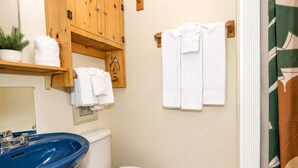 A bathroom with a blue sink, white toilet, wooden cabinets, and a towel rack.