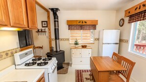 A compact kitchen with a stove, sink, and a large black chimney.