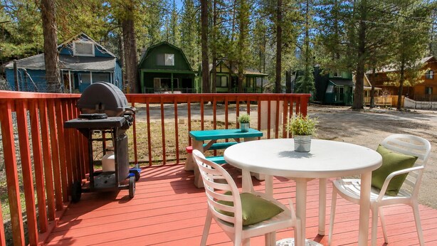 A deck with a barbecue grill, picnic table, and chairs.
