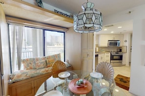 Un appartement moderne comprenant un coin repas, une cuisine et un balcon avec un canapé.
