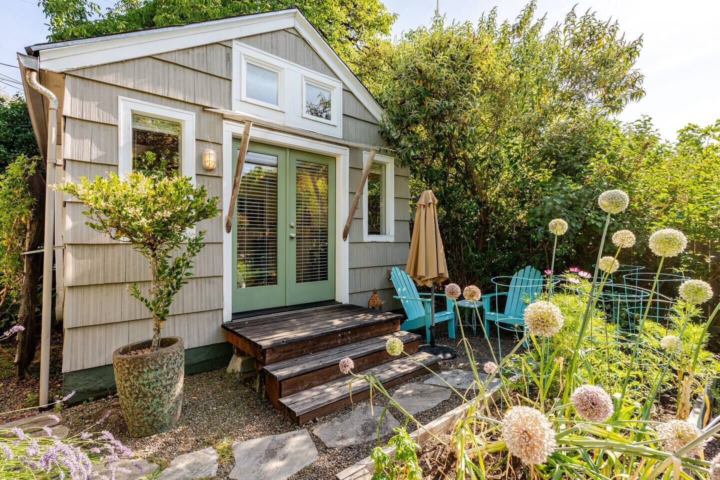 Une maison en bois avec un porche à l’avant, deux portes et une petite table entourée de chaises.