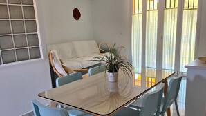 Un comedor con una mesa de vidrio, sillas azul claro y una planta en maceta.