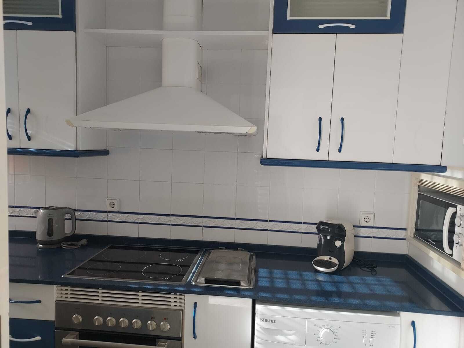 A kitchen with white cabinets, blue handles, a stove, a microwave, and a dishwasher.