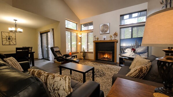 A living room with a fireplace, leather sofas, a coffee table, and a television.