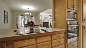 Una cocina con armarios de madera, microondas integrado y comedor con mesa y sillas.