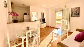 A compact living space with a dining area, a sofa, a TV, and a balcony with a view. - Beachfront apartment with large terrace (Tarifa)