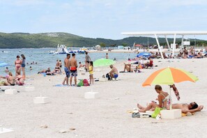 A crowded beach with people sunbathing and swimming, umbrellas, and boats in the background. - Apartment Lux in Brodarica, Sibenik, new, with terrace, parking, wi-fi, aircondi (Brodarica)