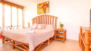 Una habitació amb un llit, taula, cadires, televisió i un quadre al mur.