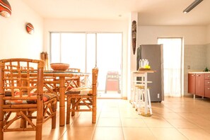 A spacious kitchen with a dining area, featuring a large table and chairs, a refrigerator, and a view through a sliding glass door.