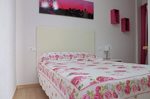A bedroom with a bed, a nightstand, a wall-mounted shelf, and a painting of a cityscape.