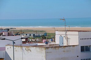Un bâtiment situé sur la côte, doté d’une antenne sur le toit, offrant une vue sur la plage et surplombant un ciel dégagé.
