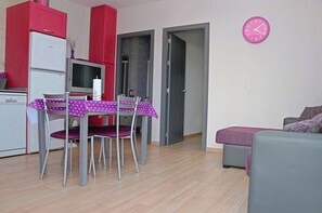 Een knus woongedeelte met een eethoek, kitchenette en een bank.