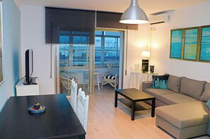 Relax in this stylish living room with a comfortable sofa, dining table, and large window offering a view of the outside.
