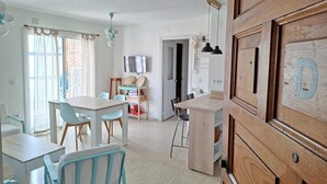 Een moderne keuken met een televisie, houten kastjes en een eethoek met een tafel en stoelen.