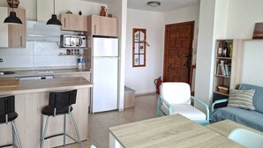 Een compacte woonruimte met een kitchenette, een eethoek en een gezellige zithoek.
