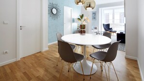 A dining area with a round table, six chairs, and a vase of flowers. - Prim Suite by FeelFree Rentals (San Sebastián)