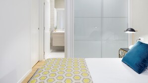A bedroom with a bed, a nightstand, a lamp, and a blue pillow. - Prim Suite by FeelFree Rentals (San Sebastián)